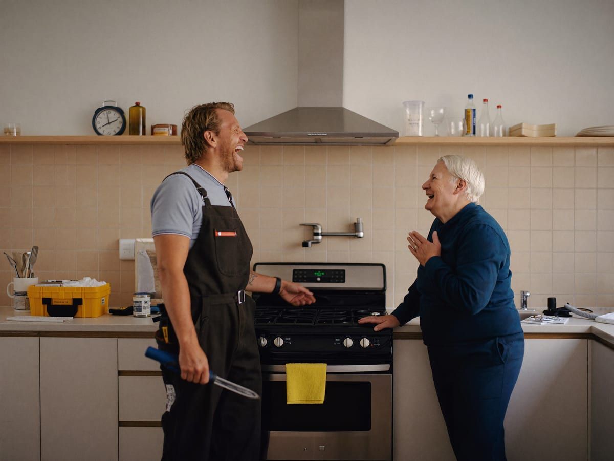 Plumber talking a homeowner through a repair at the kitchen sink